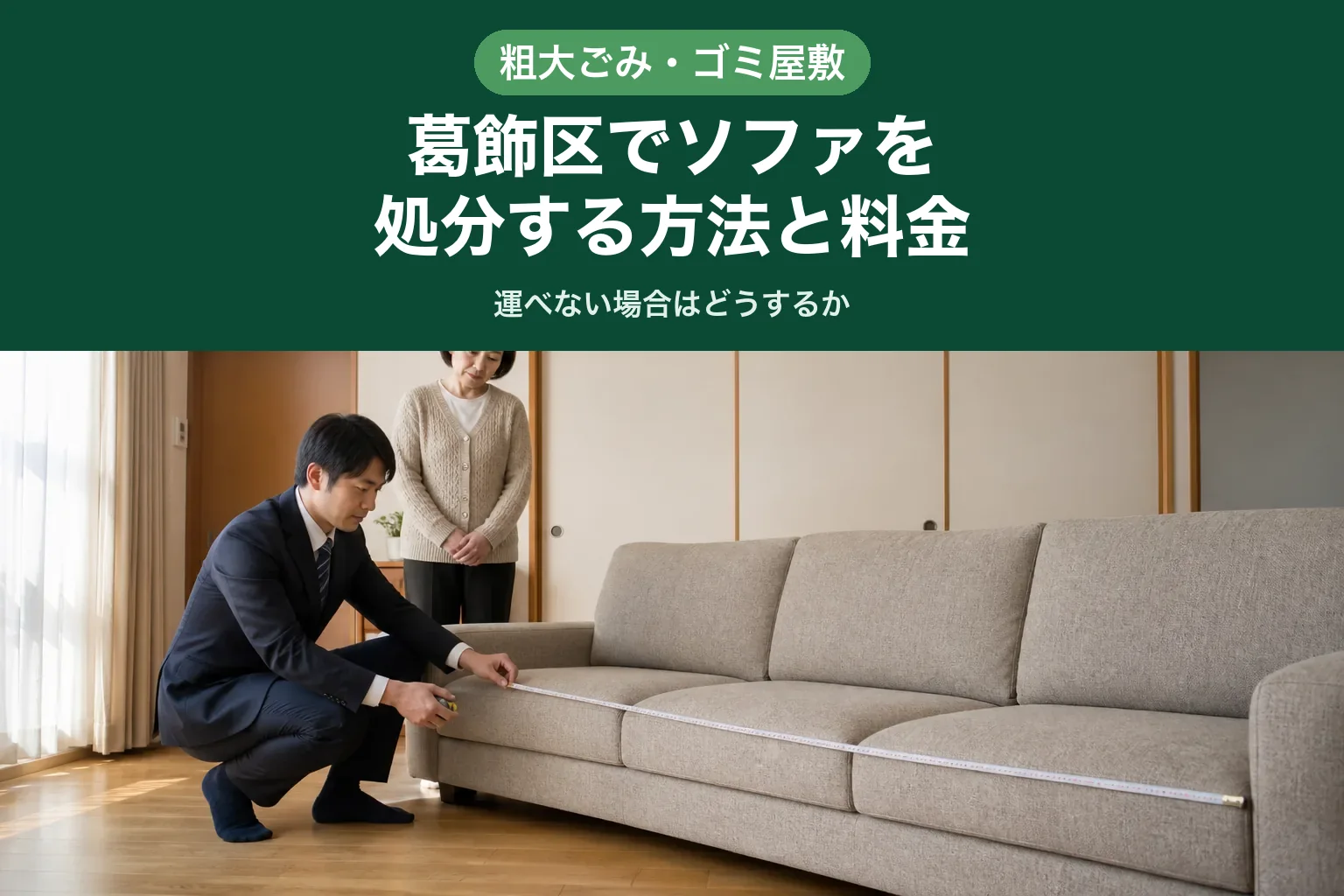 スーツ姿の査定士が、葛飾区のご自宅のリビングで三人掛けのソファの前にしゃがみ、メジャーを当てて幅を測っている様子。カーディガン姿のお客様が少し離れたところに立ち、手元を見ている