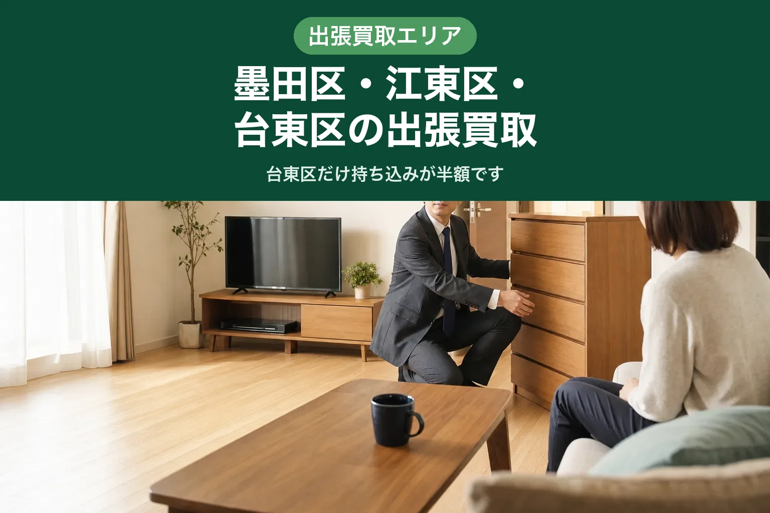 スーツ姿の査定士が、集合住宅の廊下につながるドアの前でタンスに手をかけ、搬出経路を確認している様子